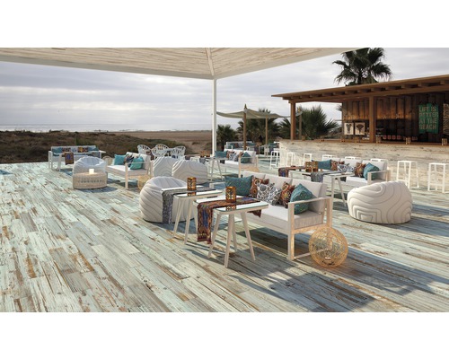 Buitenzitgedeelte met houten vloer, meubels en uitzicht op zee