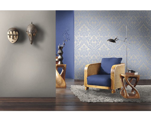 Woonkamer met bloemenbehang, fauteuil en decoratieve houten maskers