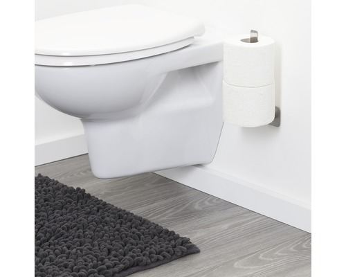Hangend toilet, toiletpapierhouder en badmat in een badkamer