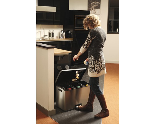 Vrouw gebruikt een afvalscheidingssysteem in de keuken