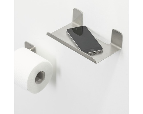 Toilet met toiletpapierhouder en metalen plank met mobiele telefoon