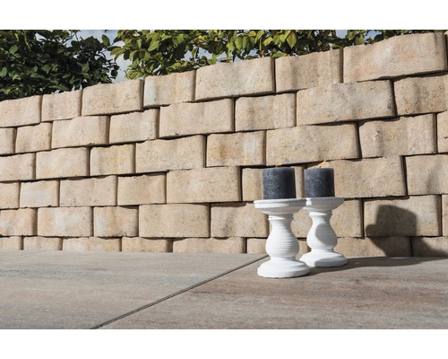 Tuinmuur van betonstenen met twee kandelaars