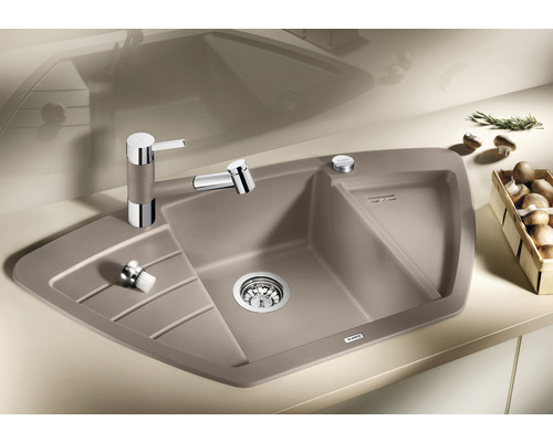 Hoekgootsteen met afdruiprek, kraan en zeepdispenser op een aanrecht.