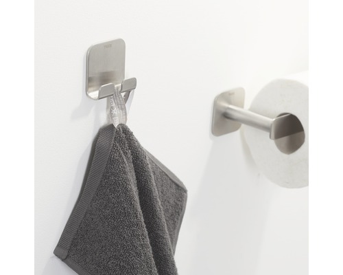 Handdoekhaak en toiletpapierhouder van metaal in de badkamer.