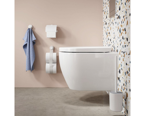 Wandhangend toilet met toiletborstel, toiletpapierhouder en handdoekhouder in badkamer.