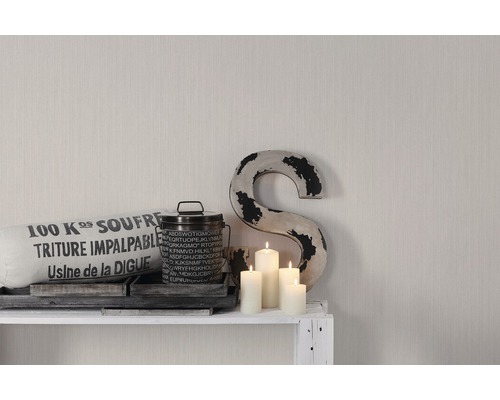 Decoratieve opstelling met kussen, blik, kaarsen en een S op een plank