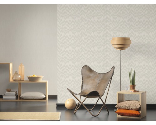 Woonkamer met patroonbehang, fauteuil en houten meubels