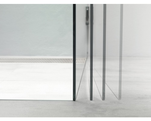 Detailopname van een douchecabine met transparante glazen wanden en een afvoersysteem in de vloer