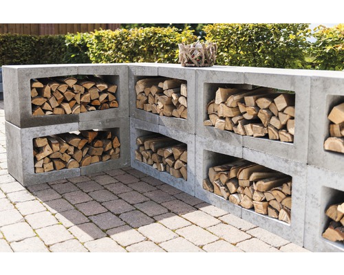 Gestapelde betonstenen als rek voor brandhout buiten.