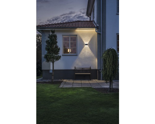 Buitenaanzicht van een huis met tuin, bank en verlichte gevel