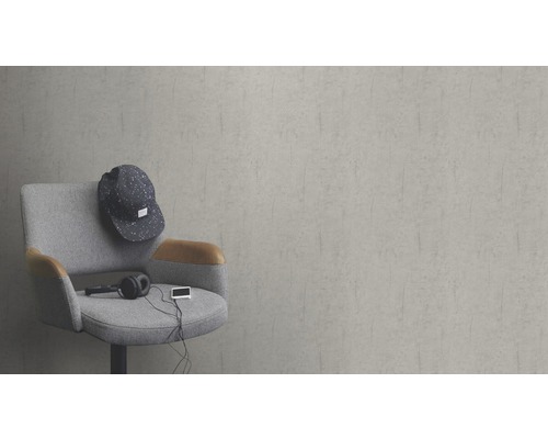 Scène met een grijze stoel, een pet, een hoofdtelefoon en een muziekspeler voor een grijze muur.