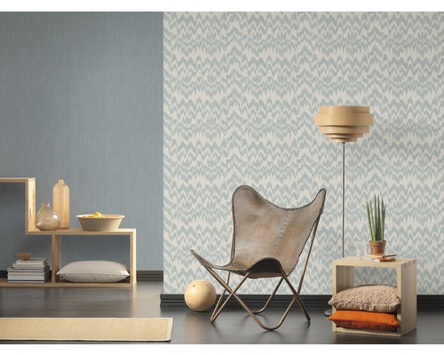 Woonkamer met patroonbehang, fauteuil en houten plank