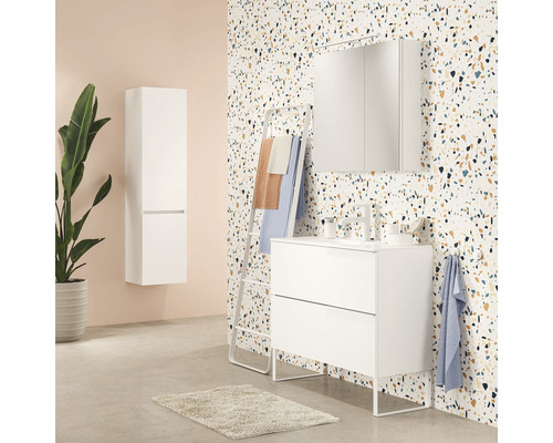 Badkamer met witte wastafelonderkast, spiegelkast, handdoekhouder en hoge kast tegen een gempatroneerde wand