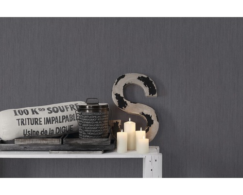 Decoratieve elementen zoals kussens, bak, kaarsen en een grote S op een witte plank voor een grijze wand