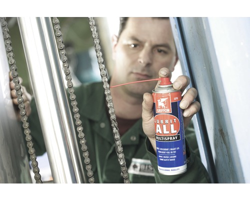 Een persoon smeert een ketting met multispray.