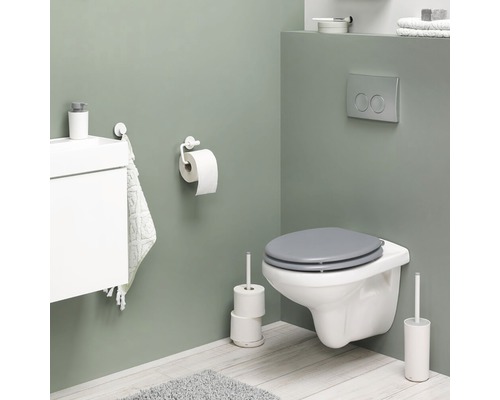 Moderne badkamer met wandcloset, toiletpapierhouder, toiletborstel en wastafelonderkast.