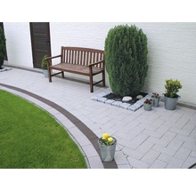 Tuinpad met bestrating, een houten bank en plantenbakken.