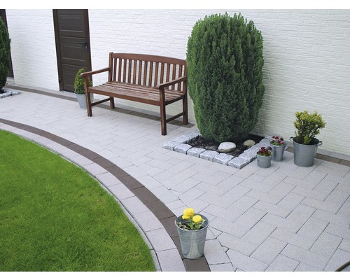 Tuinpad met bestrating, een houten bank en plantenbakken.