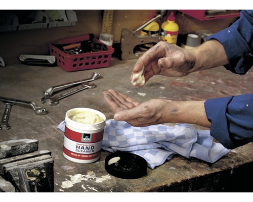 Een man reinigt zijn handen met professionele handreinigingscrème van Bison op een werkbank.