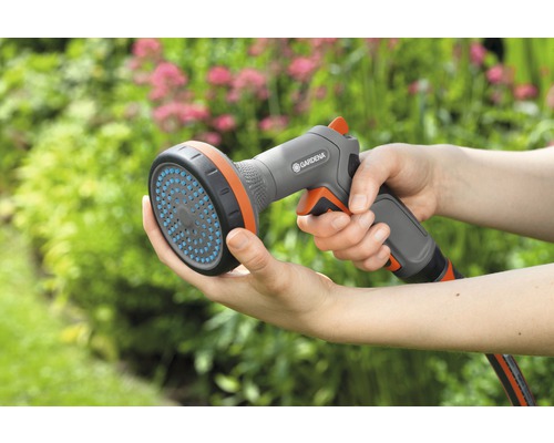 Een persoon houdt een Gardena sproeier in de hand.