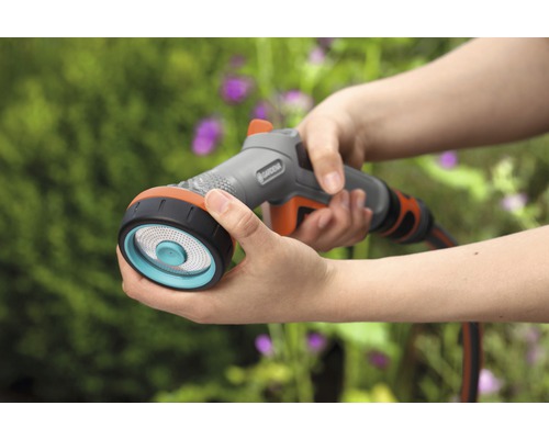 Persoon houdt een Gardena broes vast om te besproeien.