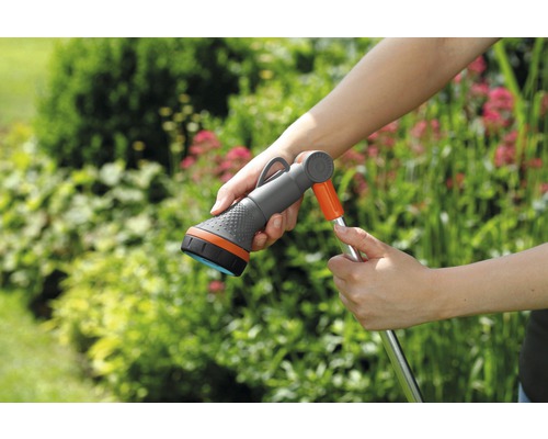 Tuinslang met sproeikop in de hand voor groene planten