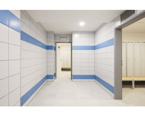 Gang met betegelde wanden en kleedkamer op de achtergrond