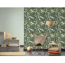 Woonkamer met Monstera blad behang, fauteuil en houten meubels voor een heldere en georganiseerde sfeer.
