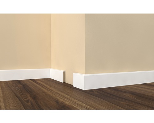 Hoek van de kamer met witte plinten en houten vloer