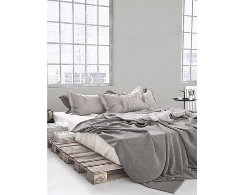 Slaapkamer met bedframe van houten pallets, beddengoed en kussens