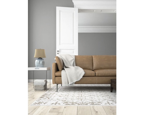 Woonkamer met leren bank, tapijt en openstaande deur