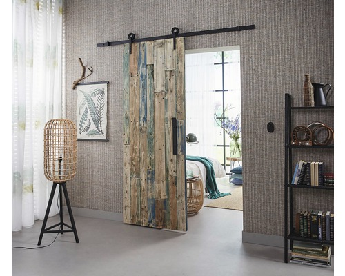 Kamer met houten schuifdeur, staande lamp en boekenkast