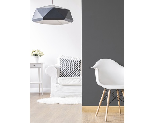 Woonkamer met geometrische hanglamp, fauteuil en stoel
