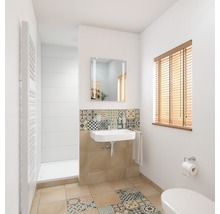 Lichte badkamer met wastafel, spiegel, radiator en tegelpatronen.