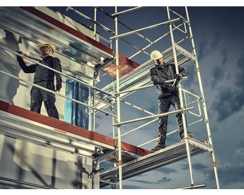 Twee bouwvakkers op een bouwsteiger voor een gebouw tijdens bouwwerkzaamheden.