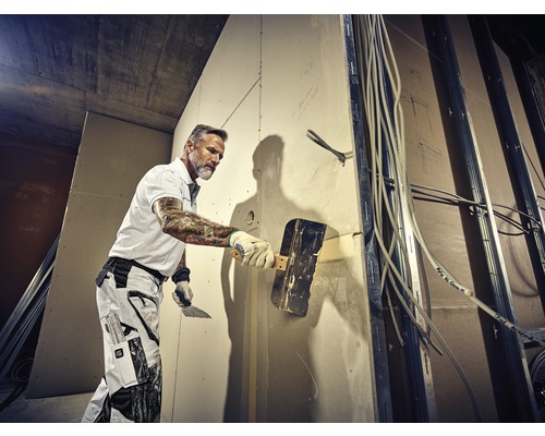 Ambachtsman plamuurt een muur op een bouwplaats