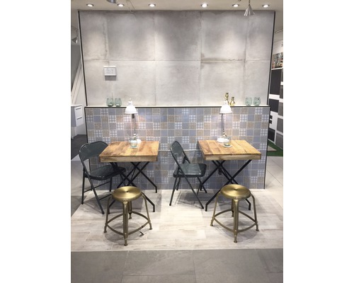 Showroom met twee tafels en zitplaatsen, betegelde achtergrond en verlichting.