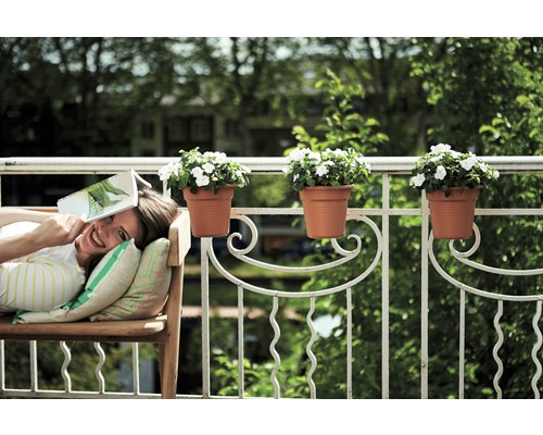 Vrouw ontspant op een bank op het balkon met bloembakken aan de reling