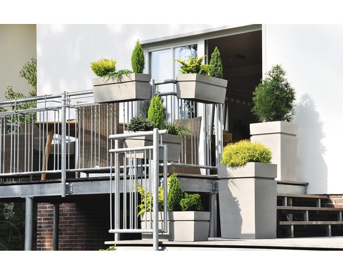 Balkonscène met diverse beplante plantenbakken in verschillende maten en vormen op een balkon met een zitgedeelte.