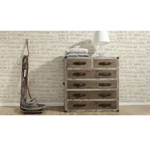 Ladekast met laden, lamp, kussens en decoratie voor een stenen muur