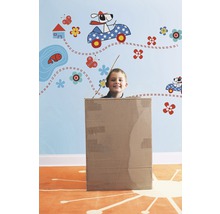 Jongen in een kartonnen doos voor een muur met muurstickers.