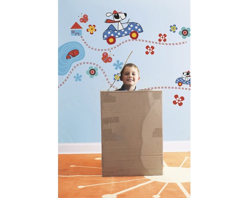 Jongen in een kartonnen doos voor een muur met muurstickers.