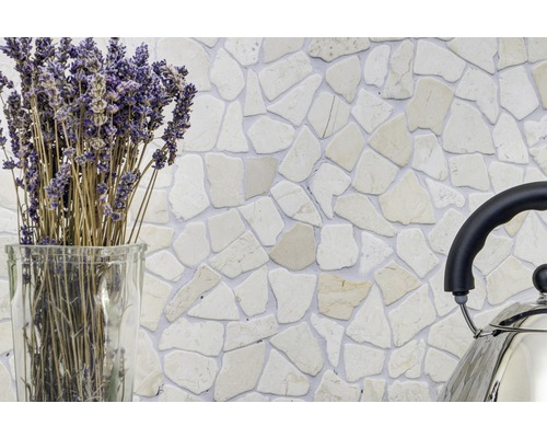 Decoratieve wand met natuursteen mozaïektegels in een interieur, aangevuld met lavendel in een glazen vaas en een roestvrijstalen ketel.