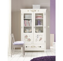 Decoratieve vitrinekast met florale elementen in een lichte ruimte.
