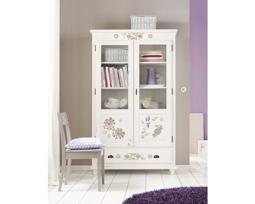 Decoratieve vitrinekast met florale elementen in een lichte ruimte.