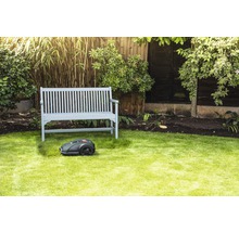 Scene met een robotmaaier voor een houten bank in een tuin.
