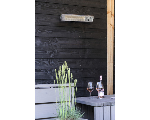 Terrasscène met terrasverwarmer, tafel, fles wijn en glazen tegen een donkere houten achterwand