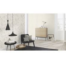 Woonkamer met patroonbehang, zwarte fauteuil en twee hanglampen