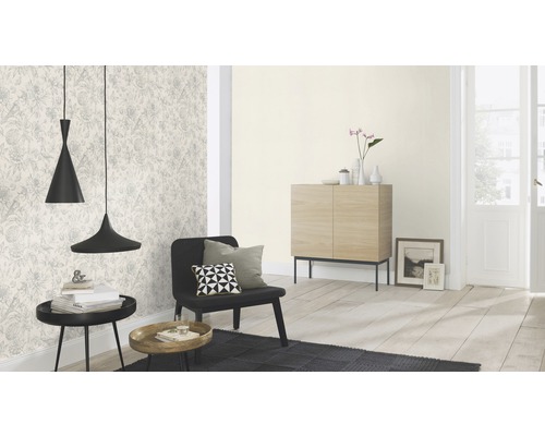 Woonkamer met patroonbehang, zwarte fauteuil en twee hanglampen