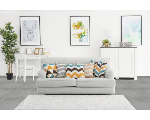 Woonkamer met bank, kussens, vloerkleed, tafel, stoel, commode en decoratie